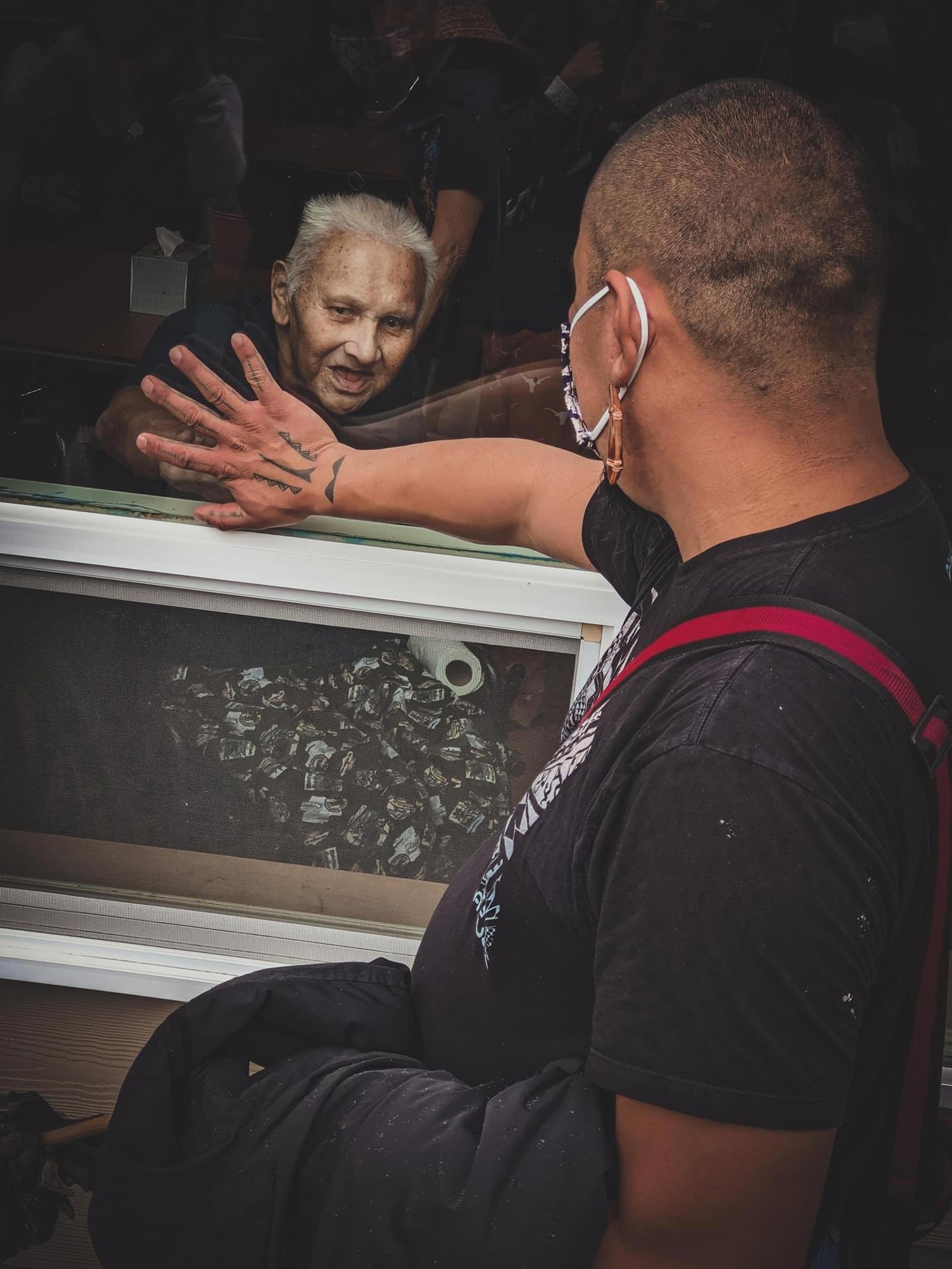 two men meet hands through a window