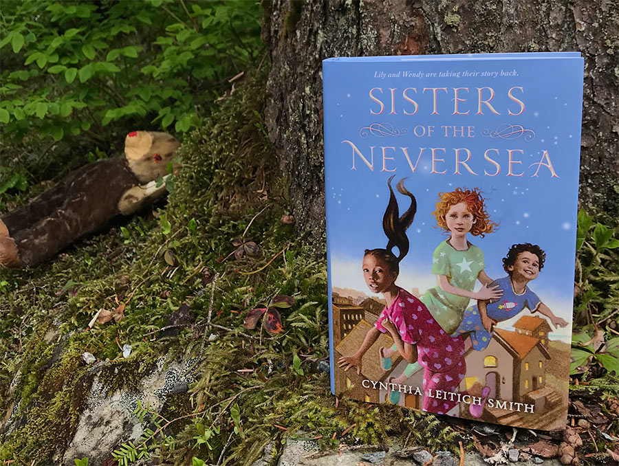 Sisters of the Neversea book sitting up against a tree