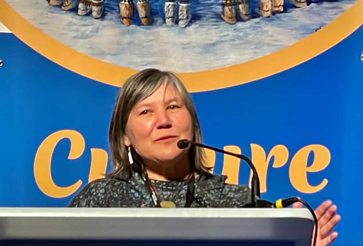 Landscape close-up photograph of Valerie Nurr’araluk Davidson, Yup’ik, keynote speaker talking into a microphone at a podium at the National Indian Health Board annual conference held in Anchorage in May.