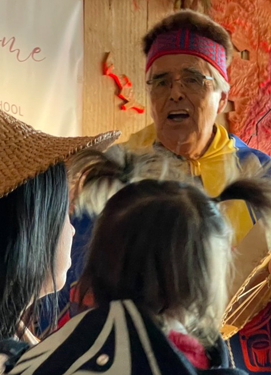 close view of artist Robert Davidson wearing a headdress and other traditional Haida clothing while performing in a dance