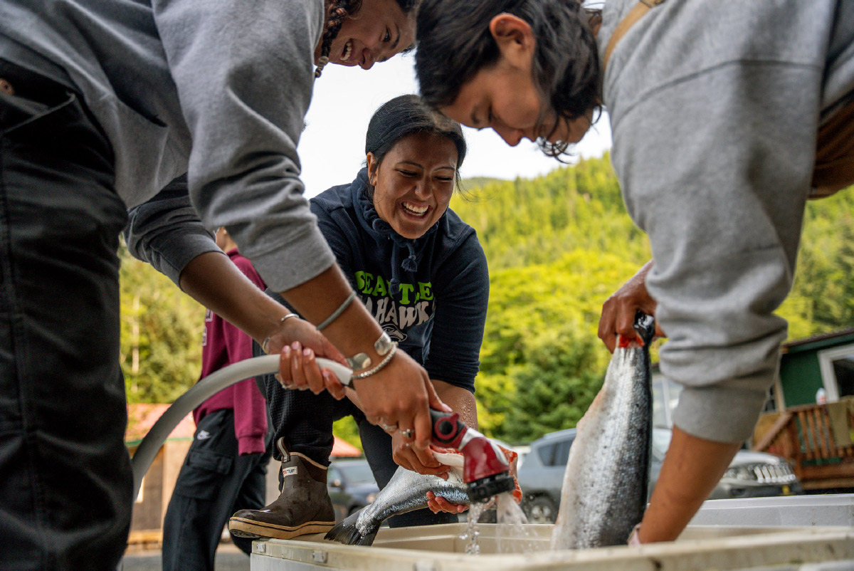 Alaska Youth Stewards crew holding fish and water hose